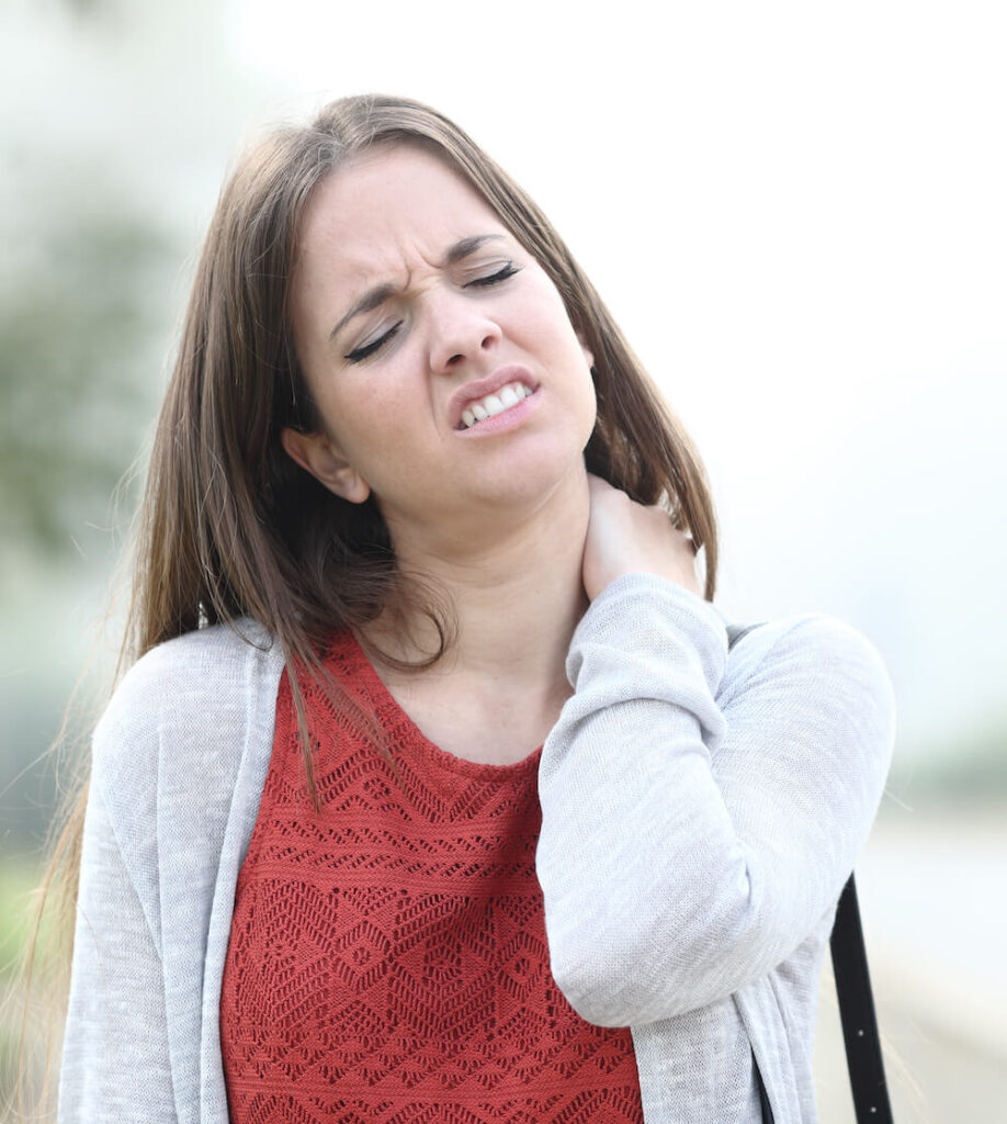 woman holding her one hand to her neck pain